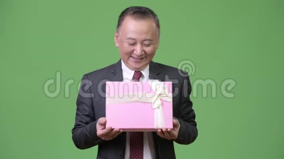 成熟的日本商人绿色背景的礼品盒视频的预览图