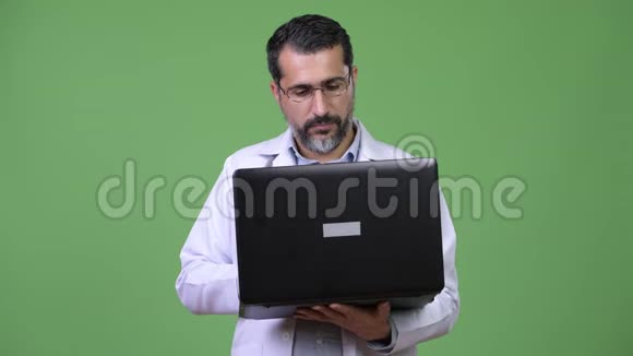英俊的波斯胡子男医生在用笔记本电脑思考视频的预览图