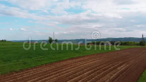在一个有小房子的村庄里鸟瞰绿色的田野山丘和树木波兰视频的预览图