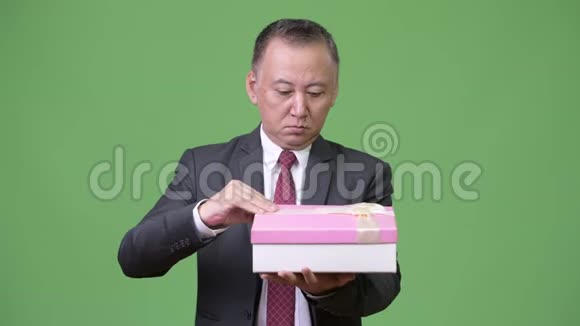 成熟的日本商人绿色背景的礼品盒视频的预览图