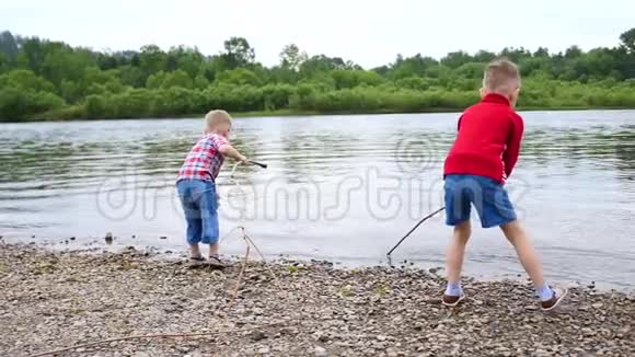 两个孩子在河岸上玩耍扔石头泼水美丽的夏日风景视频的预览图