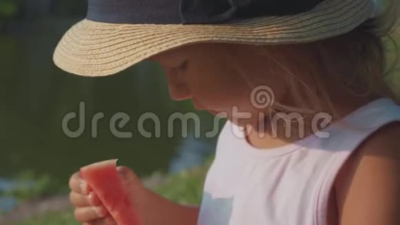 美丽可爱的小女孩快乐地吃西瓜的肖像特写视频的预览图