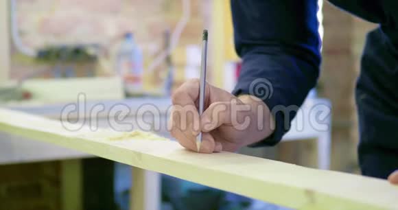 木工车间的工人用铅笔在木板上做记号特写镜头视频的预览图