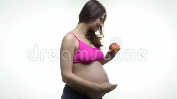 一个穿粉色上衣的孕妇咬苹果视频的预览图