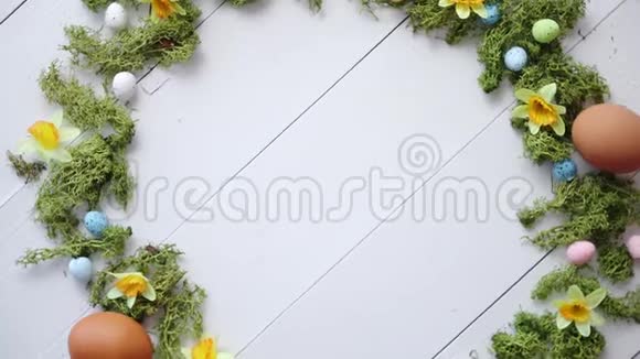 白色木桌背景上彩色装饰复活节彩蛋花圈视频的预览图