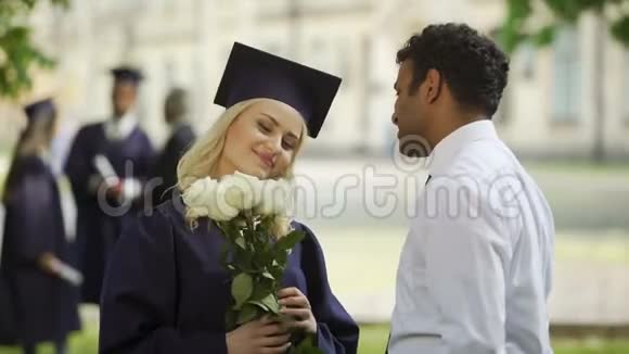 女毕业生带着鲜花与男朋友交谈教育视频的预览图