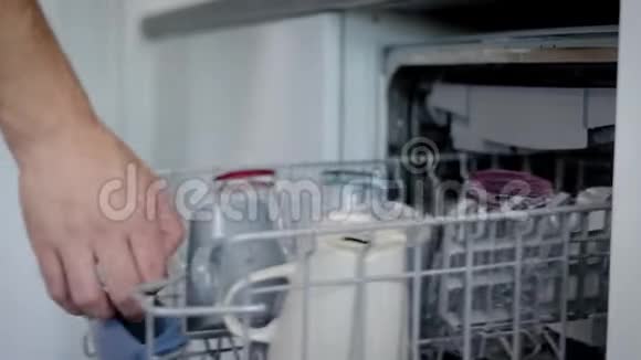 男人正在厨房里从洗碗机里拿出一个餐具清洗干净后用手特写放在桌子上视频的预览图