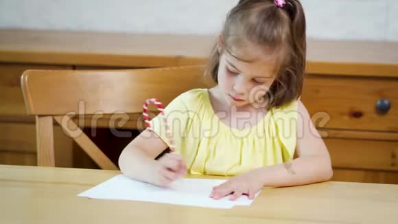 小女孩穿着黄色的连衣裙用铅笔在纸上画画视频的预览图