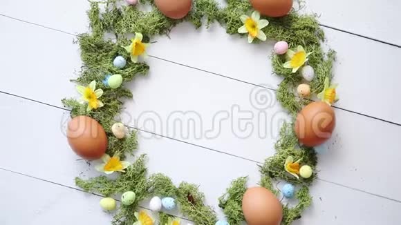 白色木桌背景上彩色装饰复活节彩蛋花圈视频的预览图