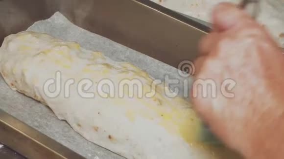 女厨师烘焙苹果Strudel女性双手用蛋清刷涂在面团上视频的预览图