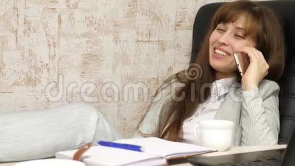 漂亮的女商人打电话光着脚坐在椅子上休息喝茶喝咖啡视频的预览图