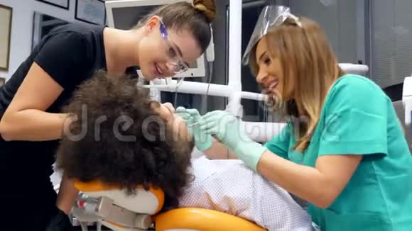 一位女牙医和她的助手检查一位年轻人的牙齿视频的预览图