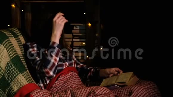 躺在沙发上躺在毯子下看书翻阅书页的女人视频的预览图