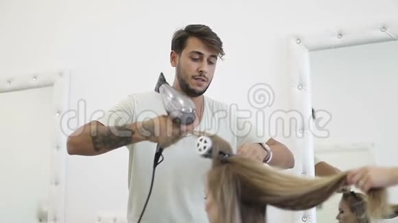 土耳其男理发师吹干女性的长发视频的预览图