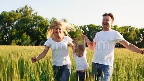 幸福的家庭爸爸妈妈和儿子在情感上散步在新鲜空气中的绿色田野里奔跑和享受生活蓝色视频的预览图