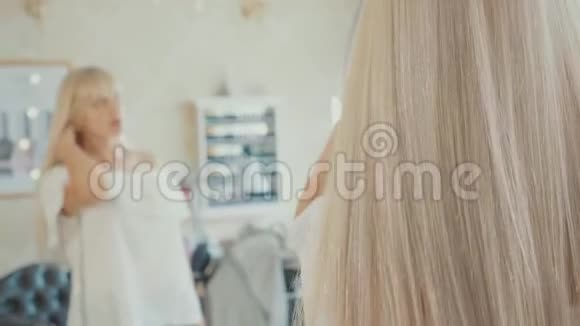 年轻女子照镜子梳洗发后纠正发型视频的预览图