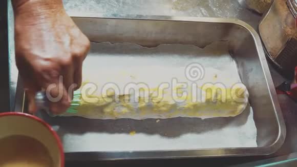 女厨师烘焙苹果Strudel女性双手用蛋清刷涂在面团上视频的预览图