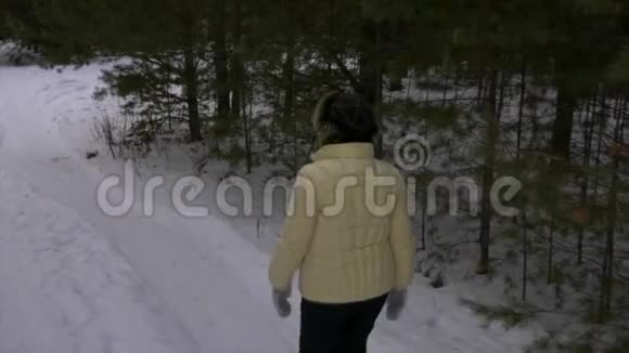 老年妇女在针叶林散步时触摸树枝松树视频的预览图