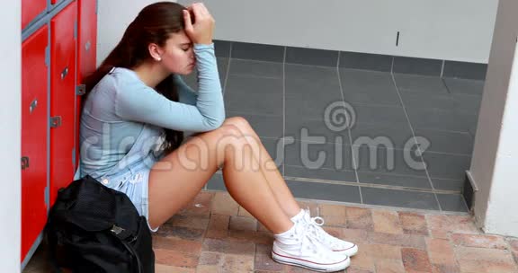 伤心的女学生独自坐在储物柜附近视频的预览图