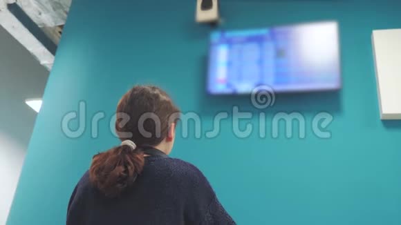 年轻的旅游女孩看着她离开机场的航班时间表看信息板检查视频的预览图