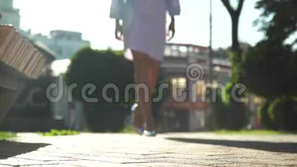 穿着高跟鞋的女人坐在公园的长凳上视频的预览图