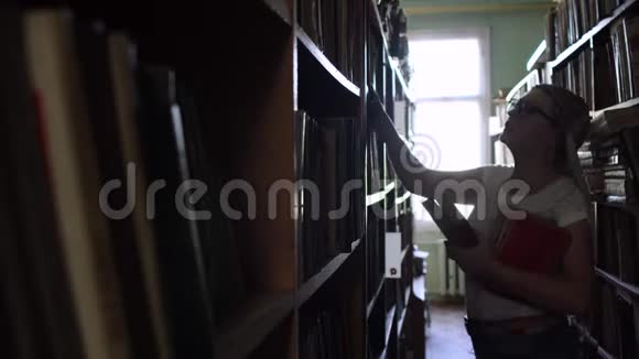 一个年轻的金发碧眼的人在图书馆里拿着书视频的预览图