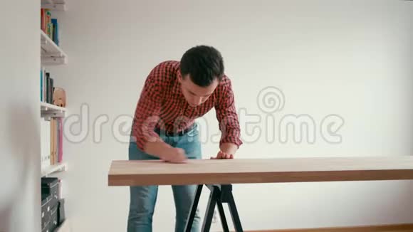 年轻人正在家里做橡树木桌男士用砂纸擦桌视频的预览图