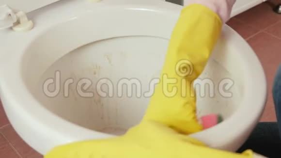 特写女士她的手在黄色橡胶手套用海绵清洗厕所侧视视频的预览图