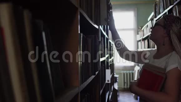图书馆里有书的两排中间美丽的金发女郎视频的预览图