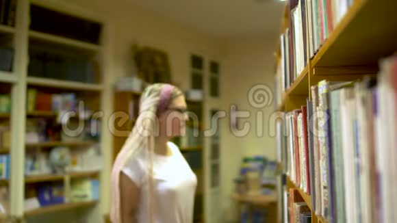 漂亮的女孩在图书馆选了一本书视频的预览图