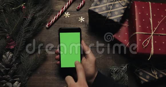 男性手滚动敲击缩放页面上的黑色智能手机与绿色屏幕铬钥匙上景垂直视频的预览图