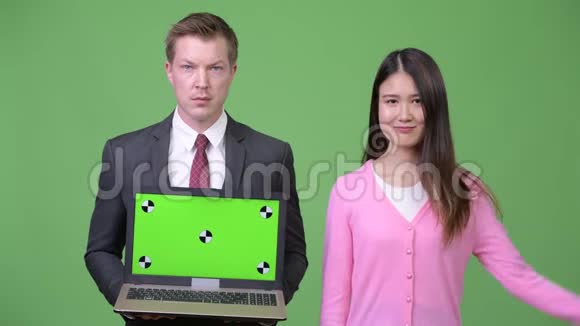 年轻的亚洲女人和年轻的商人一起展示笔记本电脑视频的预览图