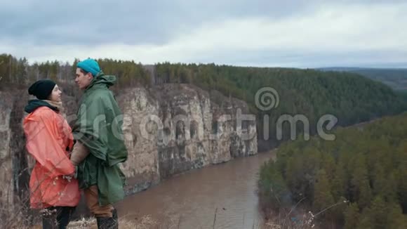 年轻的一对徒步旅行者站在悬崖边手牵着手过山河视频的预览图