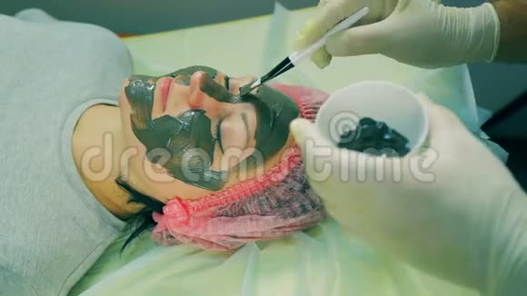 时光飞逝化妆师的男人的手放在女人的脸上一个液体黑色面具视频的预览图