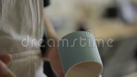 男艺术家站在陶器车间时正在杯子上涂上颜色视频的预览图
