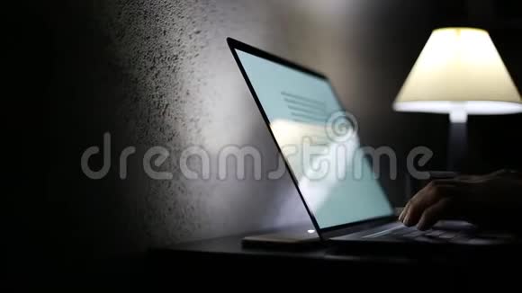在黑暗的房间里在笔记本电脑键盘上输入女性手的特写视频的预览图