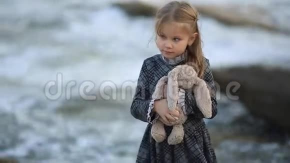 穿着连衣裙的女孩拿着天然的兔子玩具全高清视频的预览图