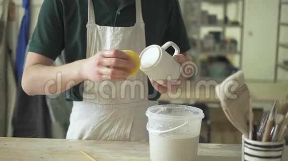 年轻的陶工正站在陶器车间的桌子旁清洗杯子视频的预览图