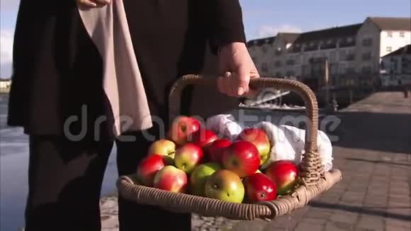 女人拿着一篮子苹果走路视频的预览图