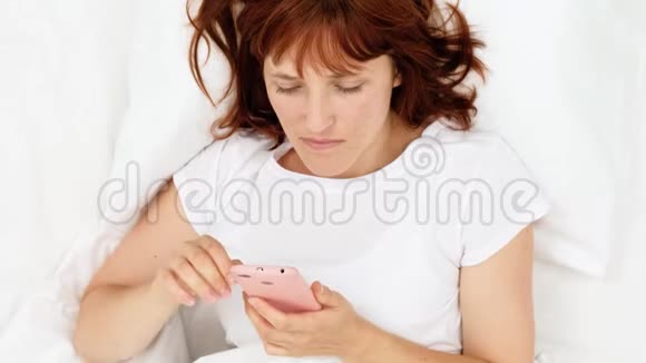 可爱的少年女孩在床上用手机拍照视频的预览图