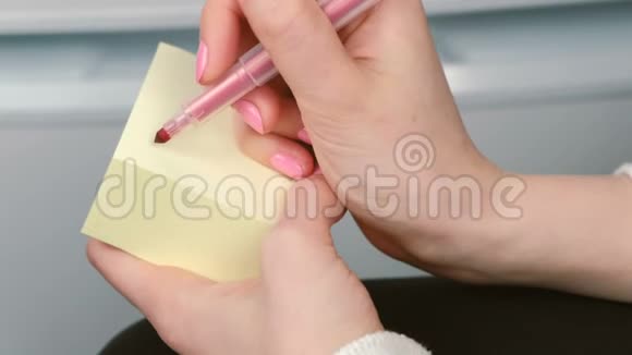 特写女人她的手写在黄色的贴纸纸上字玩得很开心视频的预览图