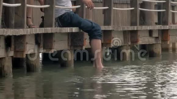 坐在木墩上双脚吊在湖里视频的预览图