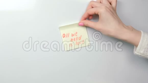 特写的女人她的手把黄色的贴纸纸和动机短语贴在白板上视频的预览图