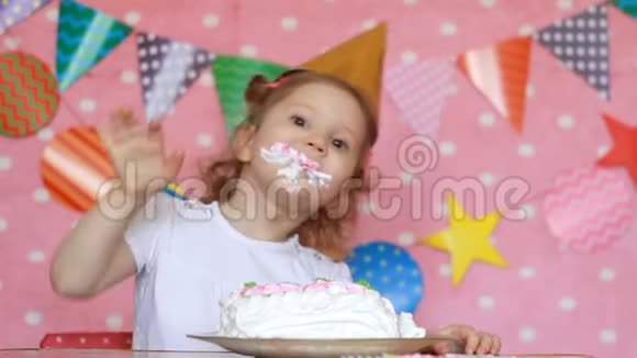 生日快乐一个可爱的小女孩吃一个脏脸和脏手的蛋糕一个在餐桌上吃甜点的孩子特写视频的预览图