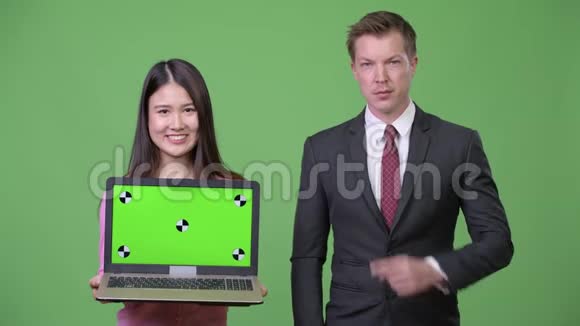 年轻的亚洲女人和年轻的商人一起展示笔记本电脑视频的预览图