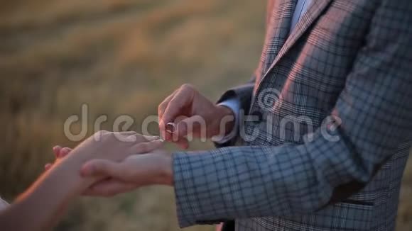 新郎把结婚戒指戴在新娘手指上日落时举行婚礼视频的预览图