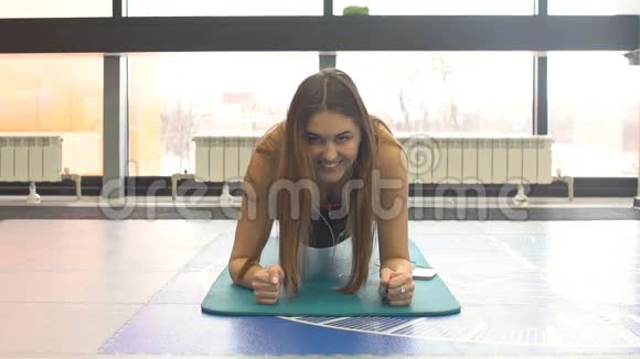 年轻女子在健身房健身垫上做核心运动视频的预览图