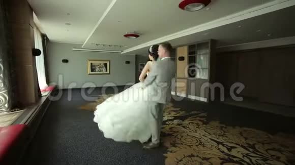 新婚快乐的新婚夫妇在一个房间里跳华尔兹里面有一个美丽的现代室内视频的预览图