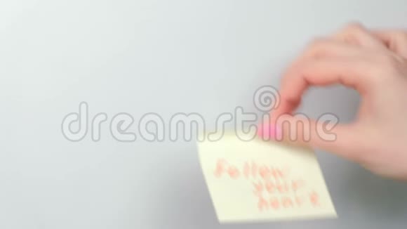 特写女人她的手贴着黄色的贴纸纸文字跟随你的心视频的预览图