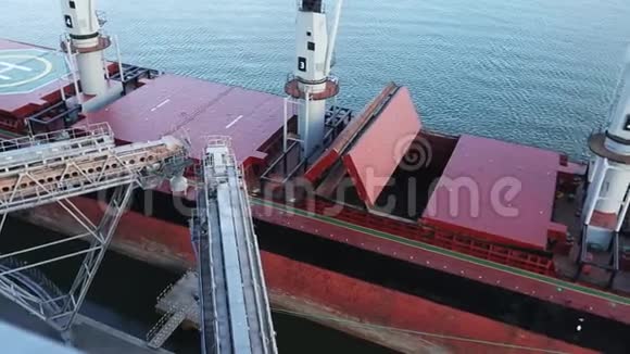 在海港的筒仓码头打开货船货舱的俯视全景谷物散装转运至船只视频的预览图